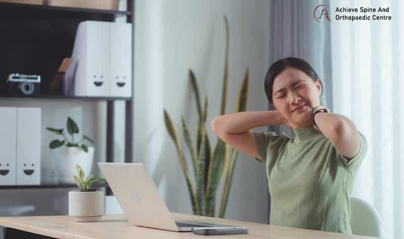 Woman experiencing neck pain while working.