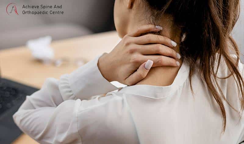 Woman experiencing neck pain while working.