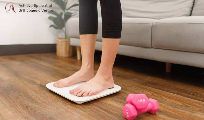 Woman on scale, highlighting weight loss and back pain links.