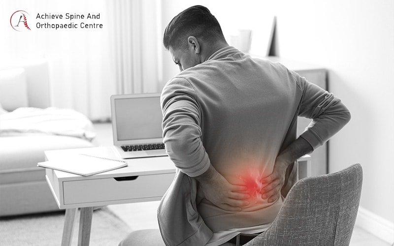 Man at desk with lower back pain needing medical advice.