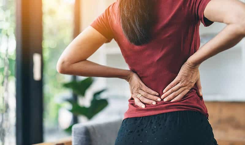 Woman holding her lower back in severe pain.