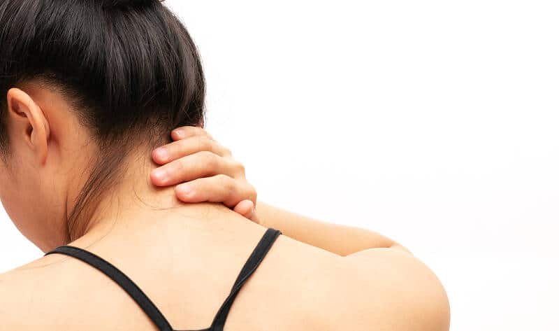 Woman touching bump at the back of her neck.