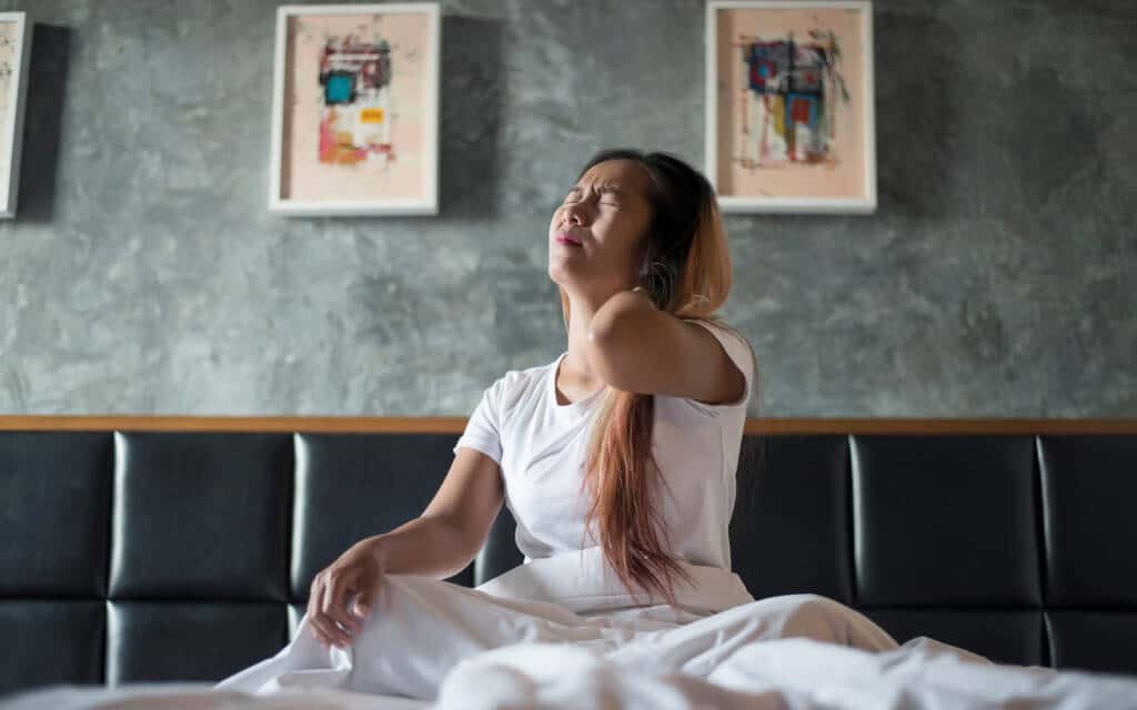 Woman holding her neck from pain when tilting head back.