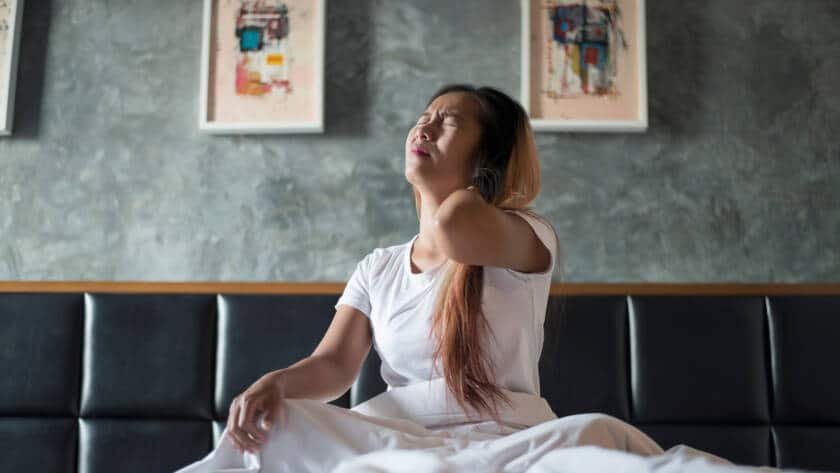 Woman holding her neck from pain when tilting head back.
