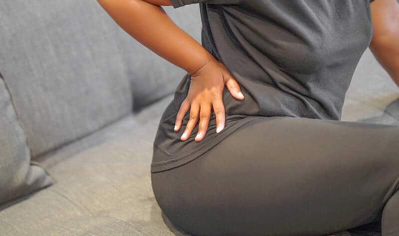 Person holding lower back suffering a sciatica flare-up.
