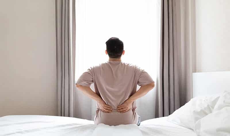 man-holding-his-painful-back-after-waking-up