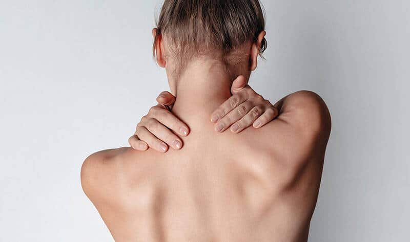 Person holding neck with uneven shoulders showing posture misalignment.